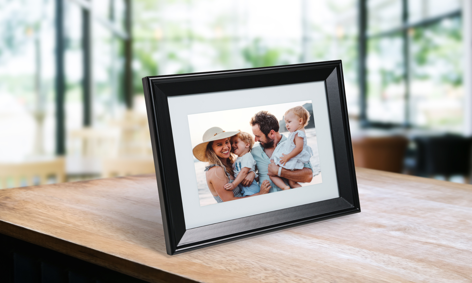 A black digital frame with a family of 4 looking at each other and smiling